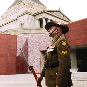 Solider standing to attention with the Shrine of Remembrance in the background