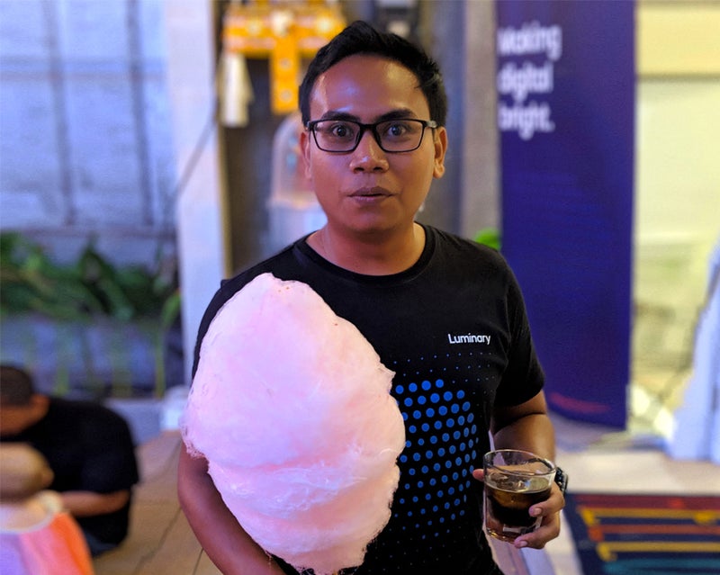 Man wearing glasses holding candy floss and a drink