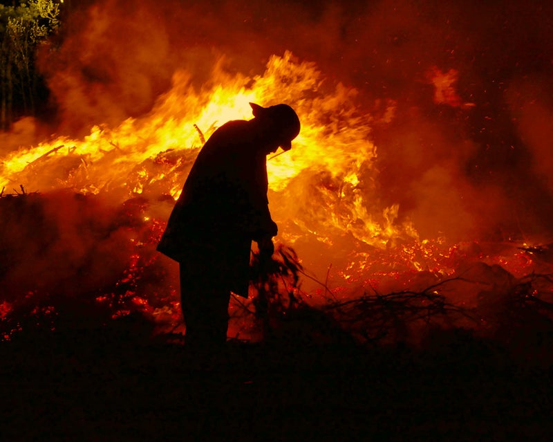 Silhouette of a fire fighter against flames