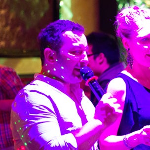 Man singing into microphone bathed in purple light