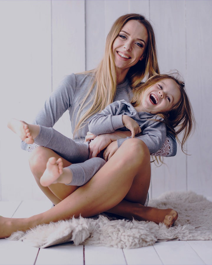 Woman sitting on the floor with a child laughing on her lap