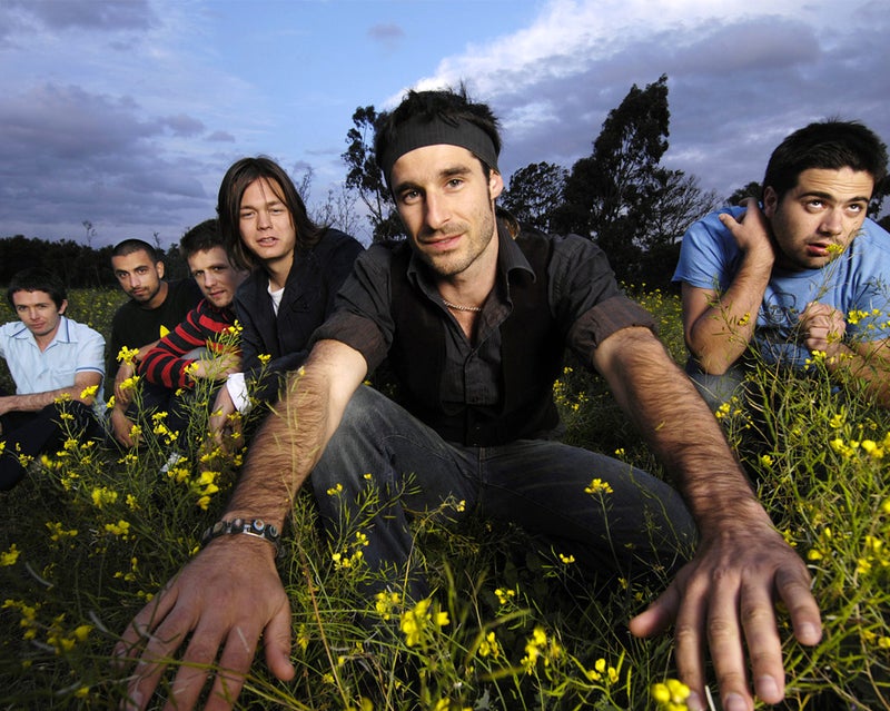 Six young men crouching in a field of yellow flowers