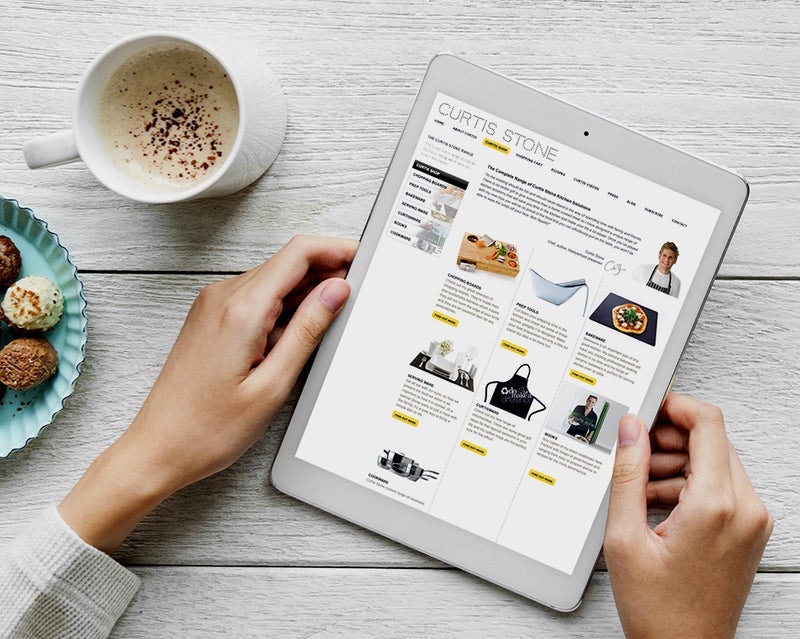 Hands holding an iPad with the Curtis Stone website open