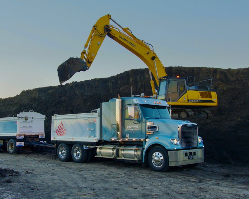 Yellow excavator loading dirt into a blue truck